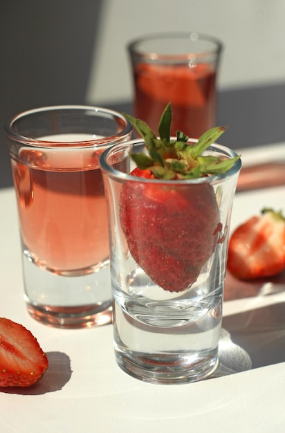 Strawberry compote tincture with ice in glass glasses with strawberries and ice cubes