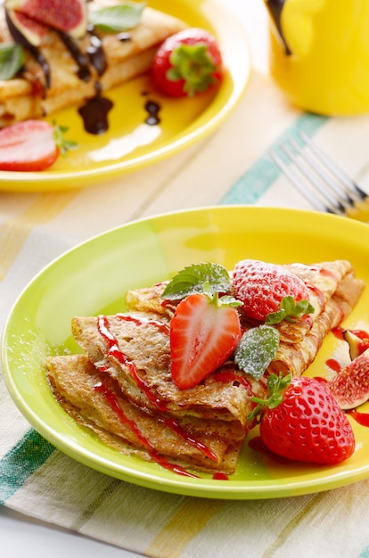 Strawberry crepes with syrup, figs and mint on the table