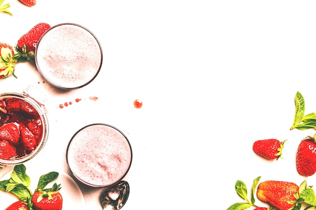 Strawberry dairy smoothies with jam berry and green mint white background copy space top view