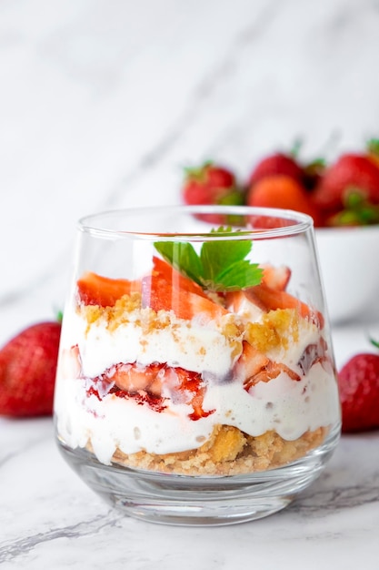 Strawberry dessert in glasses with whipped cream cookie and fresh strawberry in glass on marble