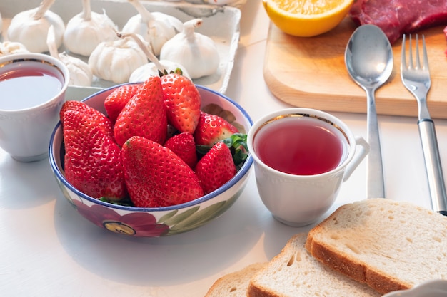 Strawberry fruit with tea in ceramic crockery on dining table