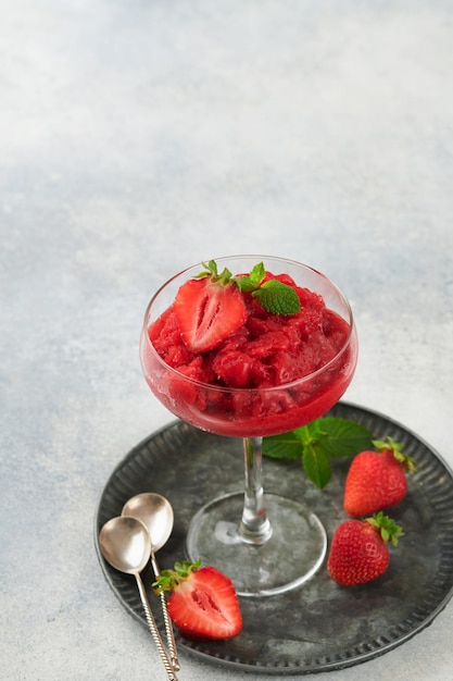 Strawberry granita or fresh berry sorbet in glass on old grey table background Texture of ice cream or sorbet Ice cream with strawberry and mint Sorbet recipe Summer treat Selective focus