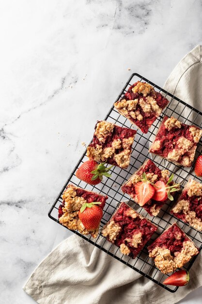 Strawberry granola bars on baking cooling rack white marble background Delisious oat squares