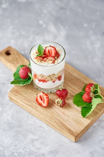 Photo strawberry granola or smoothie in glass and fresh berries on a cutting board, top view