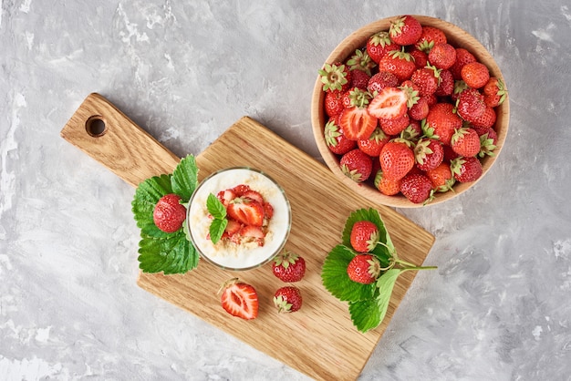 Strawberry granola or smoothie in glass and fresh berries in a wooden bowl, top view. Healthy breakfast