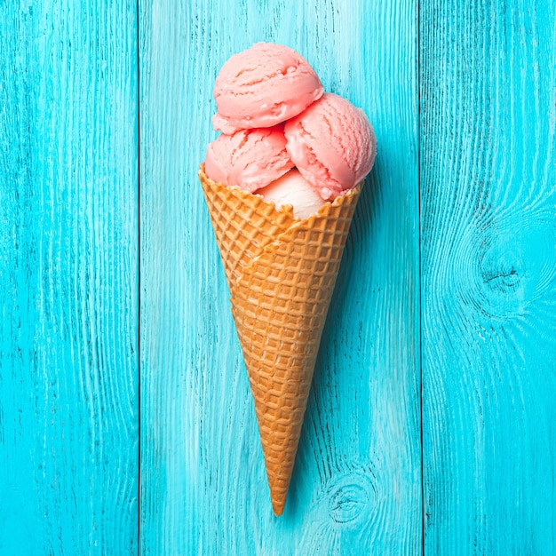 Strawberry ice cream in a waffle cone on a blue background