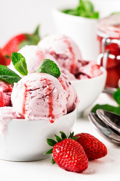 Strawberry ice cream with jam topping decorated with green mint leaves gray background selective focus