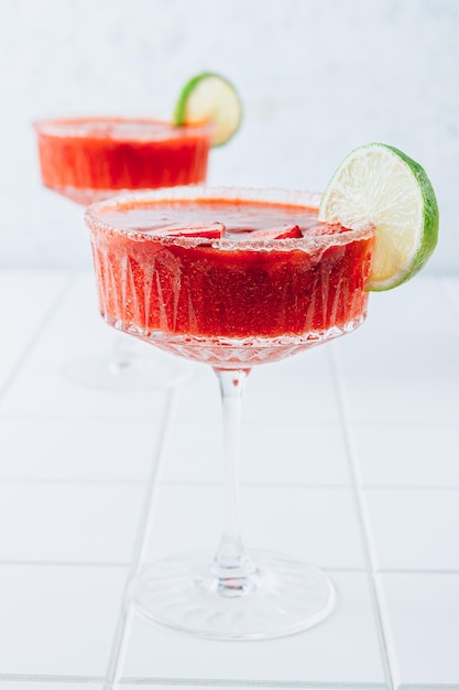 Strawberry margarita or daiquiri cocktail with lime and mint on white background