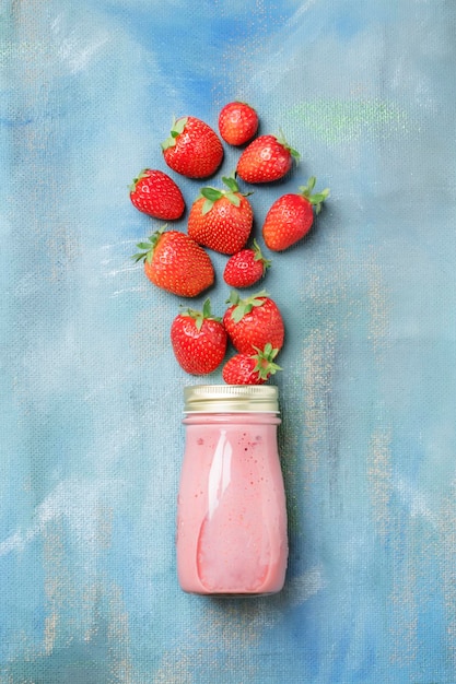 Strawberry non dairy smoothies with nut milk in bottle on blue background food and drink background flat lay