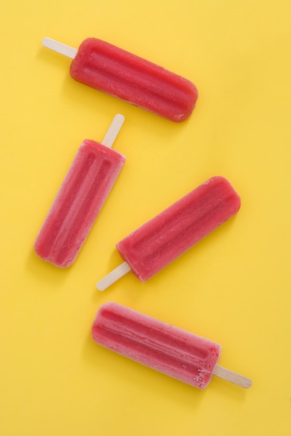 Strawberry popsicles on yellow