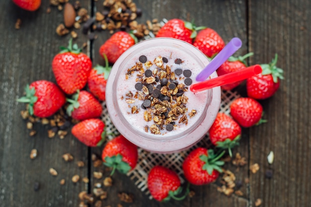 Strawberry smoothie in glass jar with chocolate chips and a straw