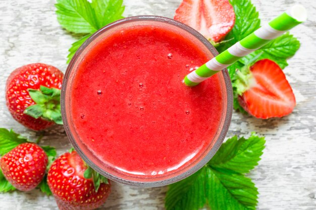 Strawberry smoothie in a glass with straw and fresh berries