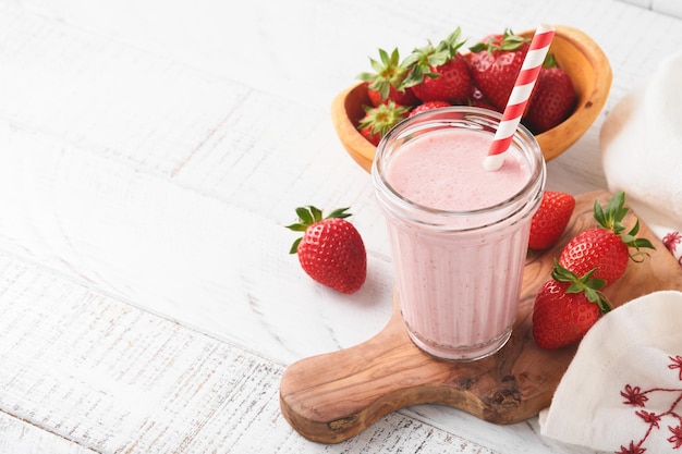 Strawberry smoothie Vegan smoothie or milkshake from strawberry banana and mint on white wooden table background Clean eating alkaline diet Top view Mock up