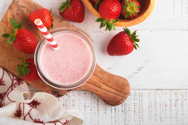 Strawberry smoothie Vegan smoothie or milkshake from strawberry banana and mint on white wooden table background Clean eating alkaline diet Top view Mock up