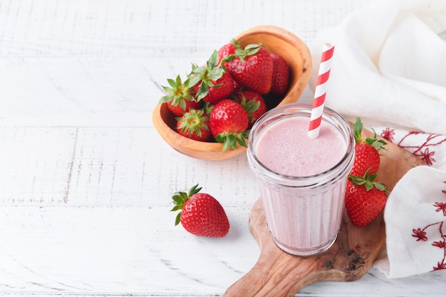 Strawberry smoothie Vegan smoothie or milkshake from strawberry banana and mint on white wooden table background Clean eating alkaline diet Top view Mock up