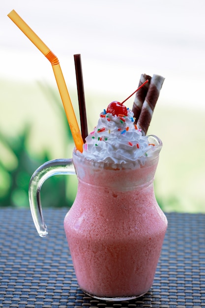 Strawberry smoothies milkshake with whip cream and cherry for topping.