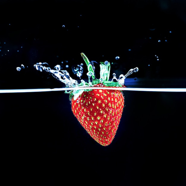 A strawberry splashing into water