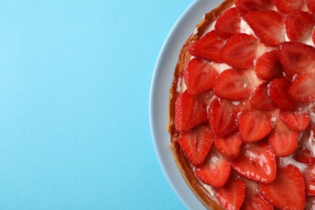 Strawberry tart on blue background, space for text.