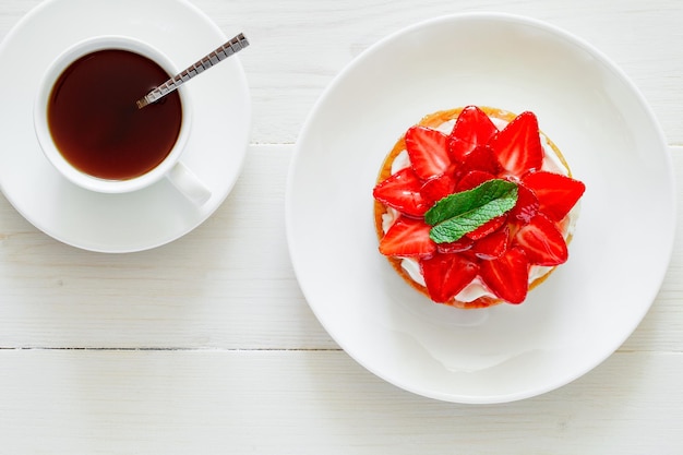 Strawberry tart cake and mug with black coffee on white board background top view space to copy text