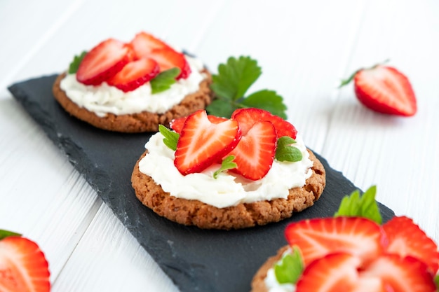 Strawberry tart with oat biscuit and whipped cream on black slate board Recipe of simple berry cake for breakfast or holiday Summer light dessert