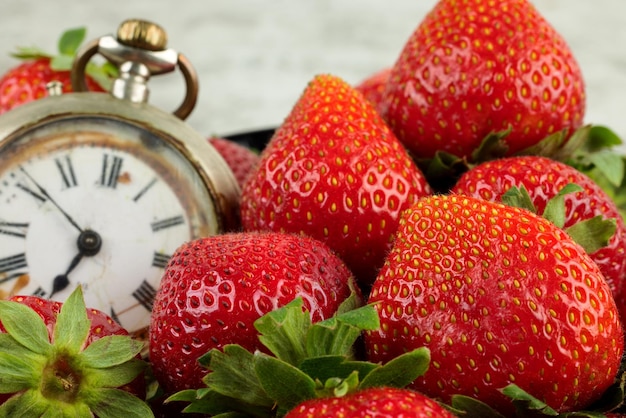 Strawberry time. Strawberries and old clock.