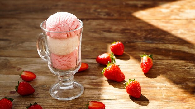 Strawberry and vanilla ice cream in a glass glass. Strawberries on wooden background