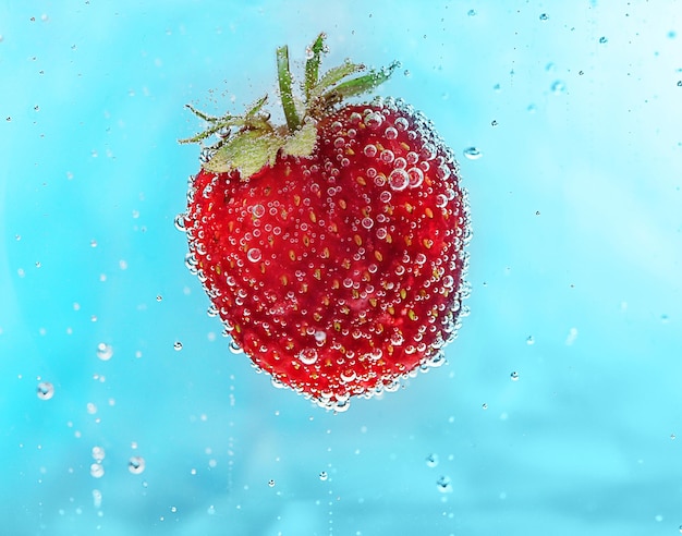 Strawberry in a water on color background