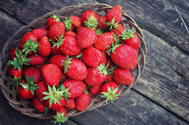 Strawberry in wicker plate on wooden background