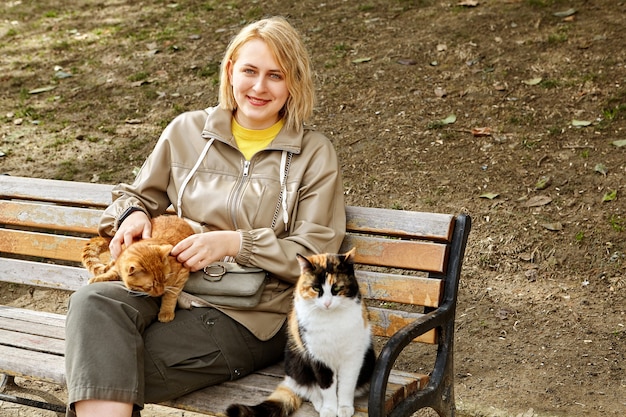 Stray Istanbul cats sit on bench near smiling young white woman.