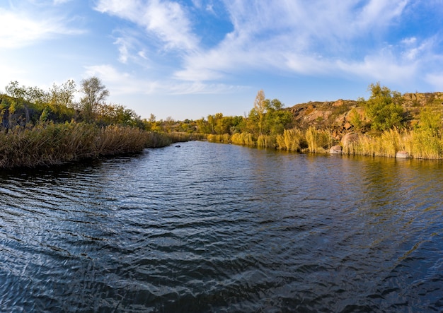 A stream flowing among huge stones covered with small dry plants in the warm evening light in picturesque Ukraine