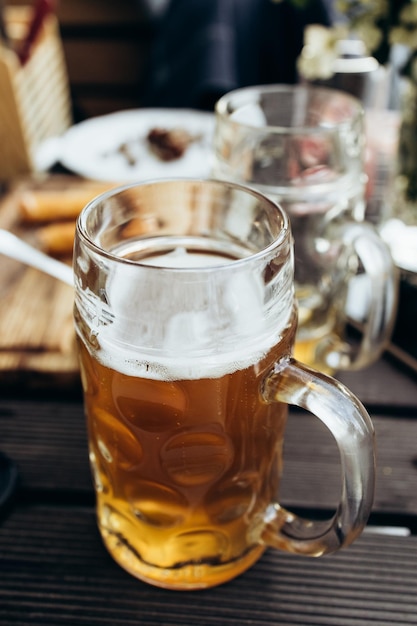 In a street cafe on a wooden table there is an incomplete mug of fresh beer