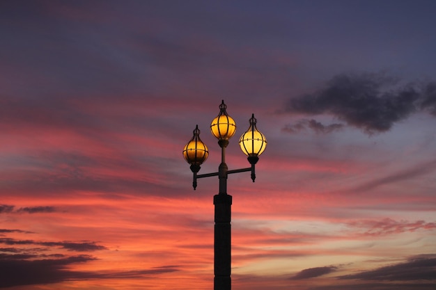 A street lamp in the evening with a colorful sky behind it.