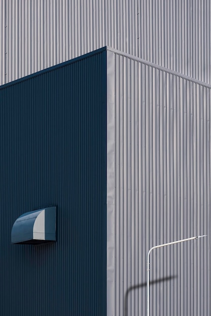 Street light post with air duct ventilation on gray corrugated metal industrial building