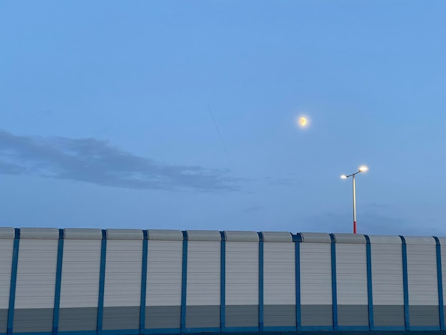 Street lights shining under dusk sky with the moon glowing