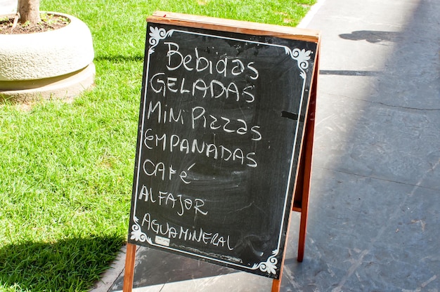 Street market sign Portuguese translation cold drinks mini pizzas empanadas coffee alfajor and mineral water