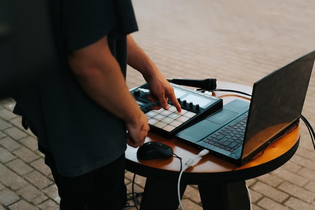 Street musician beatmaker plays hiphop on midi controller drum machine in an open air Closeup selective focus