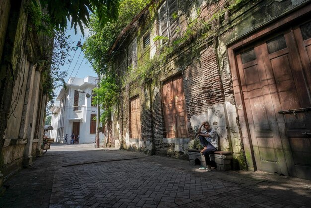 A street scene with a woman sitting on a bench in front of a building with a sign that says'the name of the place is '