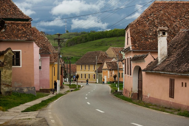 A street in a village with a green hill in the background