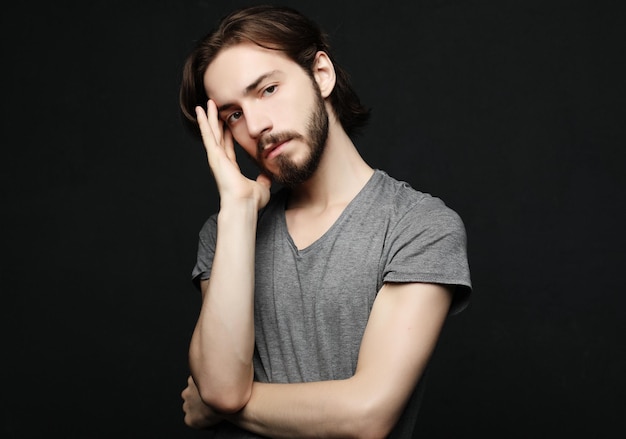 Stress headache health care and people concept unhappy man touching his forehead over black background