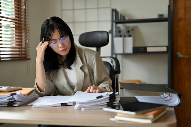 Stressed Asian businesswoman pensively thinking and planning her financial iplan