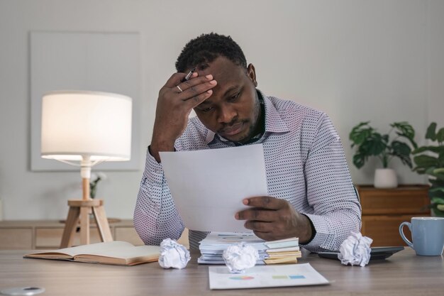 Stressed business man sitting at office workplace Tired and overworked black man Young africanamerican exhausted men in stress working on laptop computer