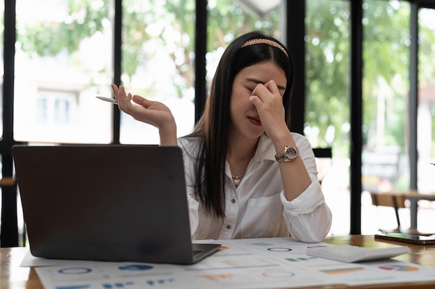 Stressed business woman working on laptop for calculation looking worried tired and overwhelmed