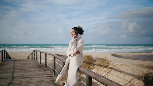 Stressed businesswoman talking smartphone on beach weekend serious woman walk