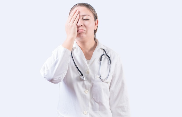 Stressed female doctor with hand on forehead isolated Exhausted young female doctor with hand on forehead