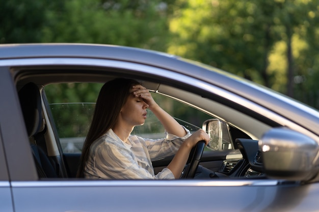 Stressed girl with headache drive car frustrated displeased young female driver suffer from illness