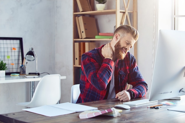 Stressed guy having a neck pain at his workplace