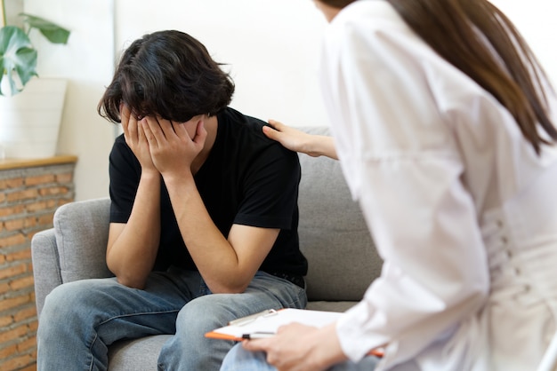 Stressed man crying and consulting problem with psychologist.