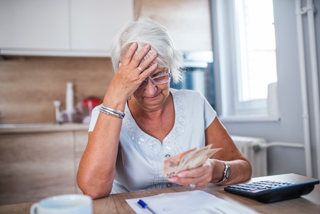 Stressed senior woman is doing banking and administrative work at home