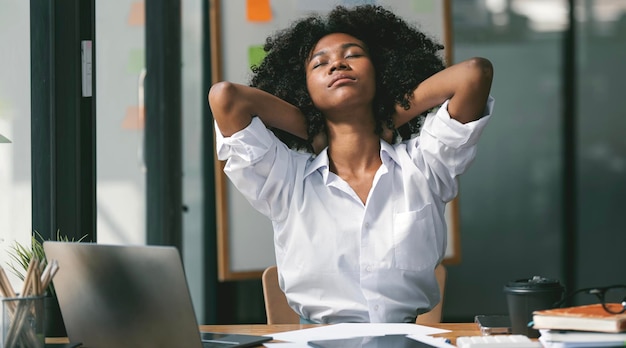 Stressed tired young Black freelance woman suffering from migraine headache at workplace