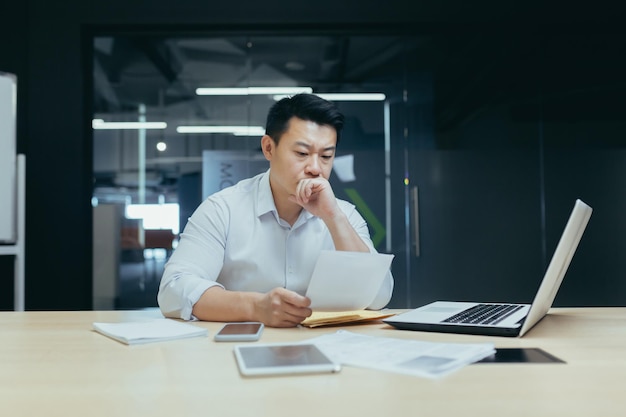 Stressed young asian businessman working from office report annoyed with low sales